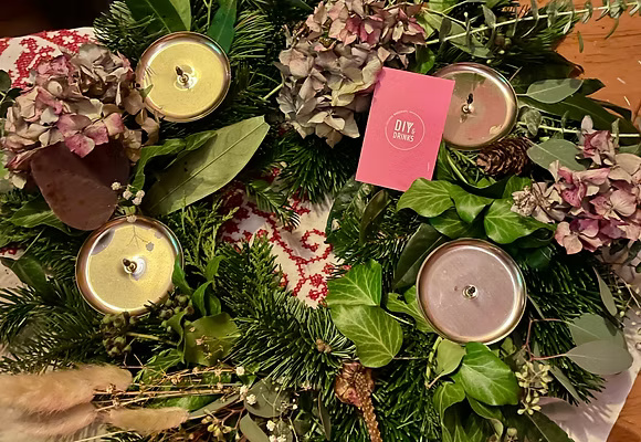 Adventskranz mit Kerzen und getrockneten Blumen.