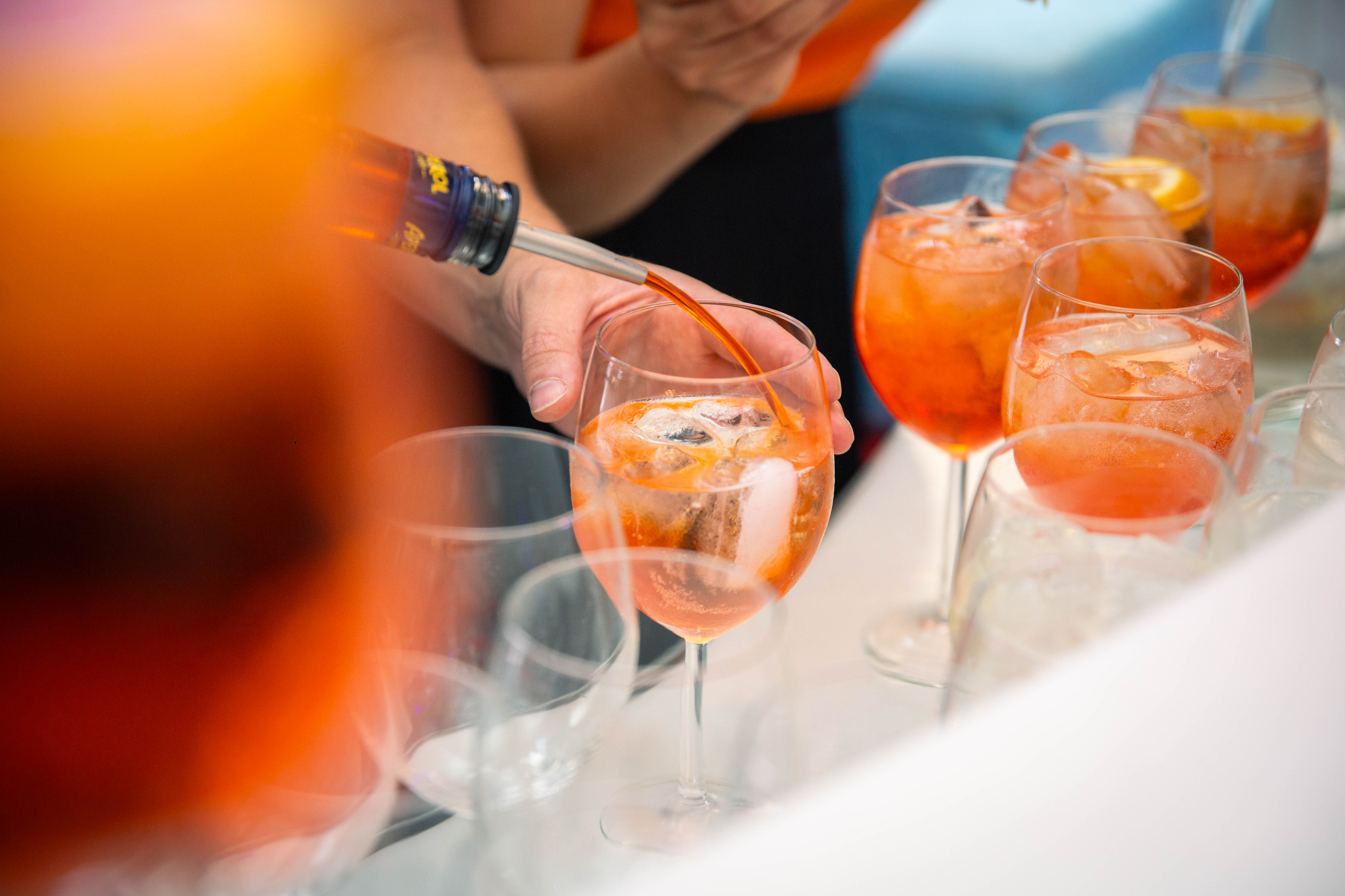 Person pouring Aperol spritz into glass.