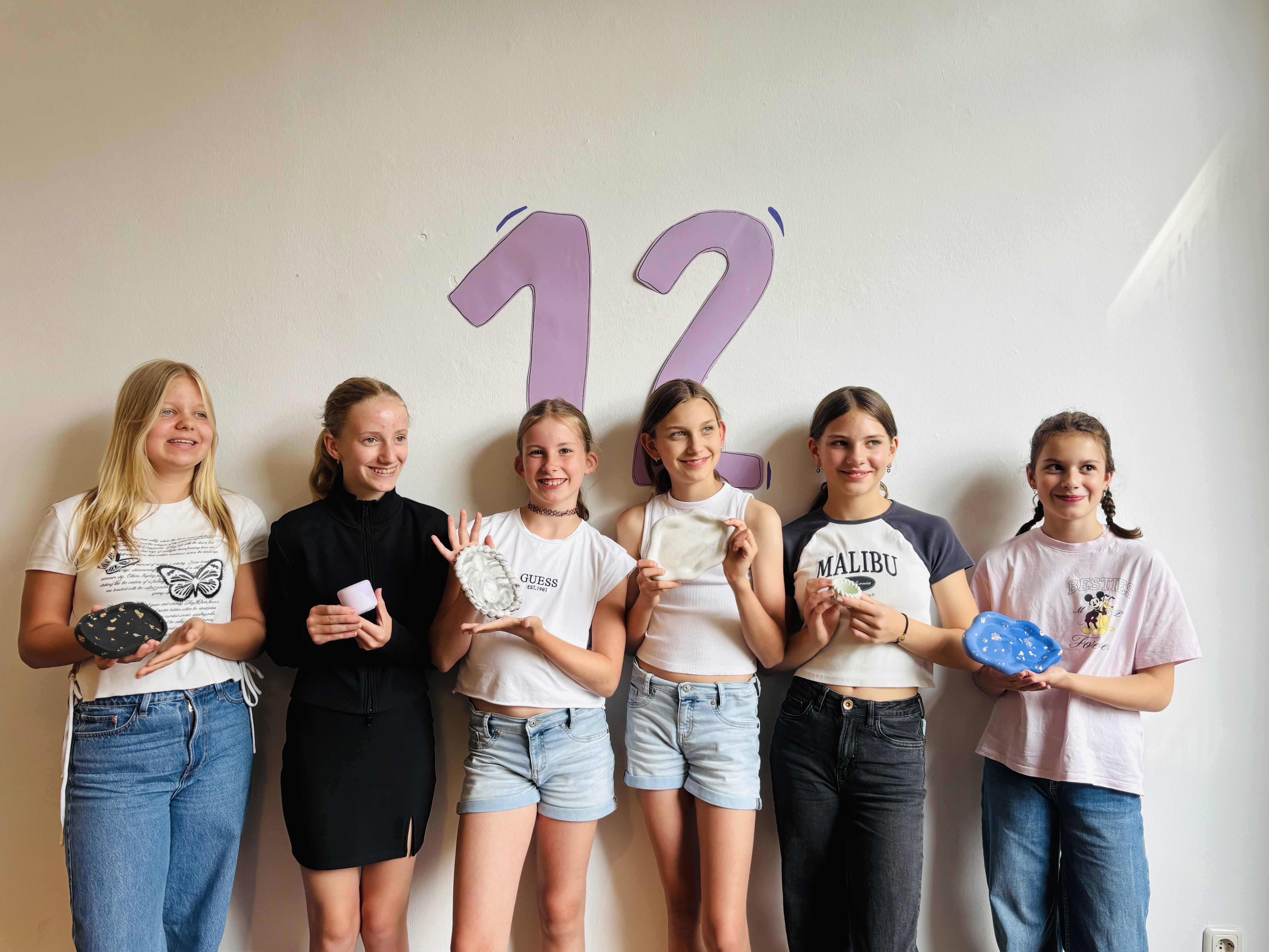 Sechs junge Leute halten Seife vor der Wand.