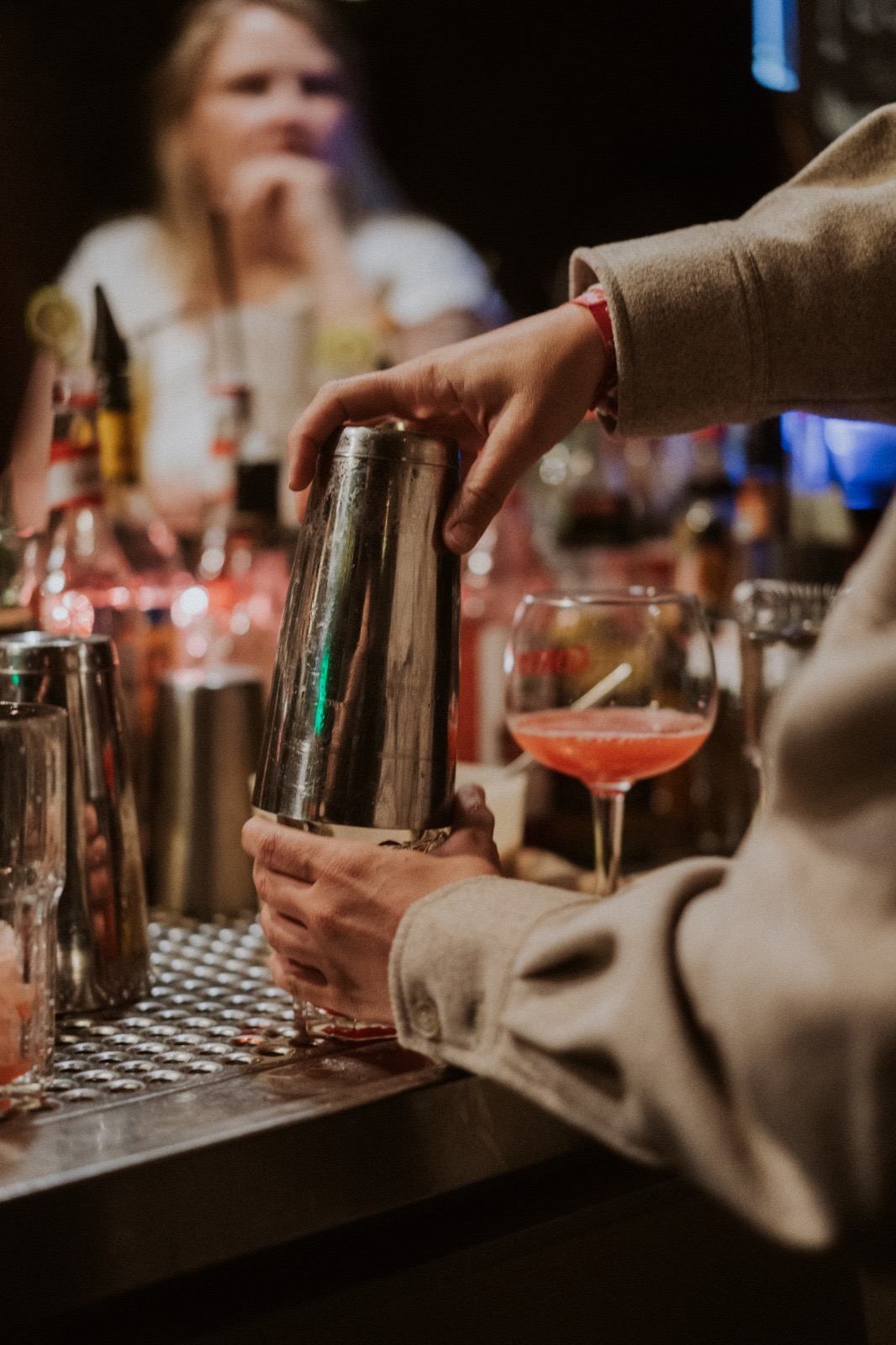 Bartender shaking cocktail shaker behind bar.