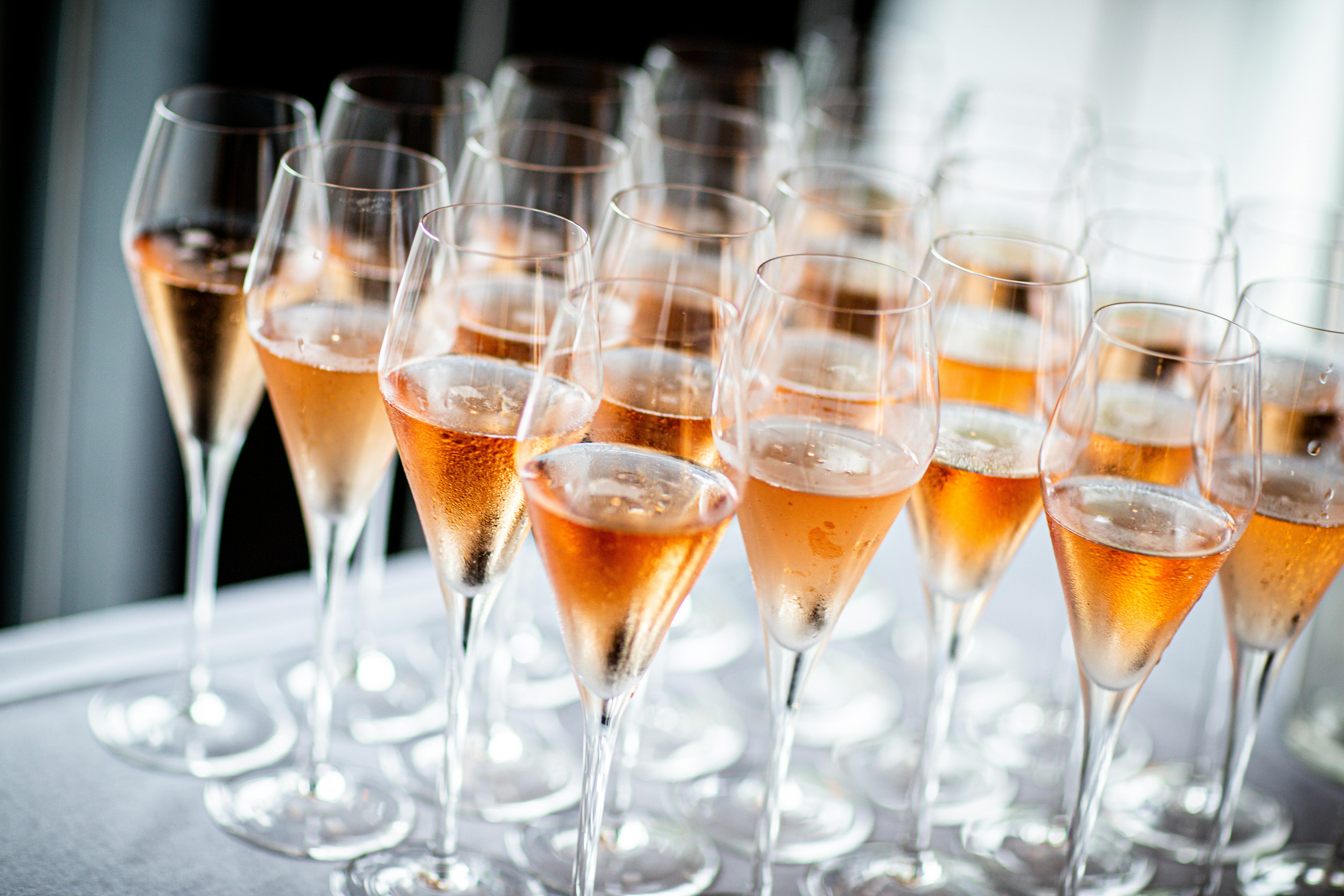 Glasses filled with rosé champagne on table.