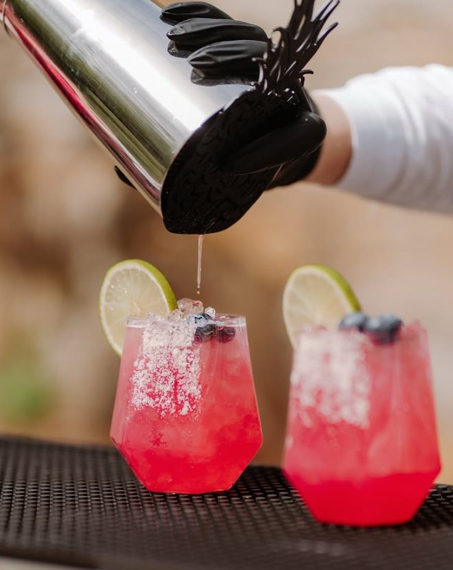 Rosafarbene Cocktails mit Limette und Blaubeeren draußen.