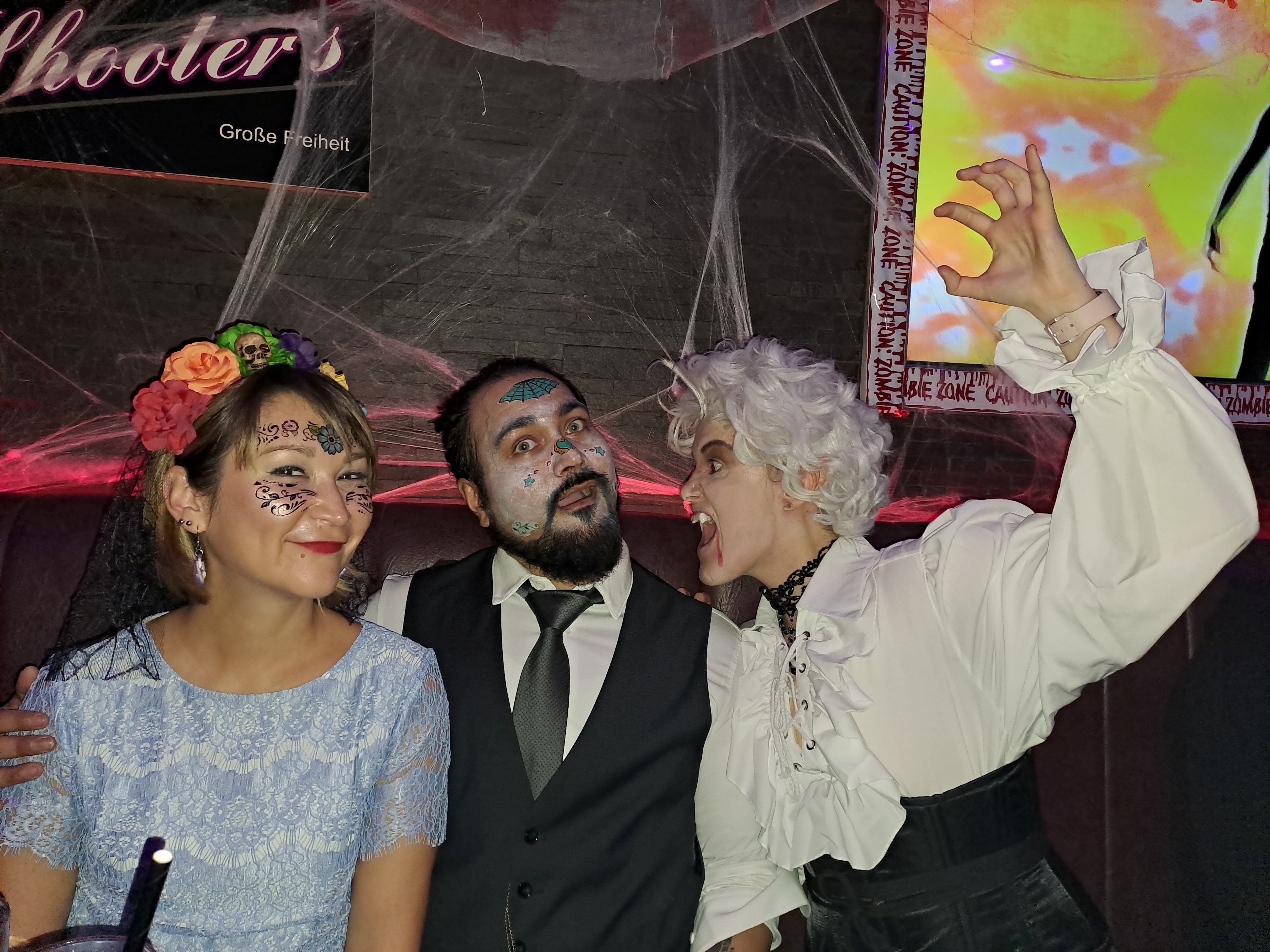 Three people in Halloween costumes indoors.